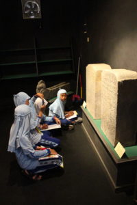 Para siswa sedang melihat prasasti di ruang koleksi arca batu