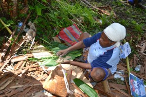 seorang mama sedang membuat sagu bungkus makanan tradisional Papua