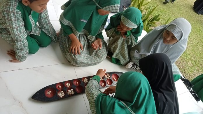 Siswa SD Islam Al-Faatih mencoba permainan congklak