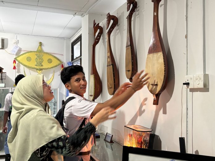 Siswa MAN Bintan sedang memperhatikan dambus (gambus) alat musik tradisional dari Kepulauan Bangka Belitung